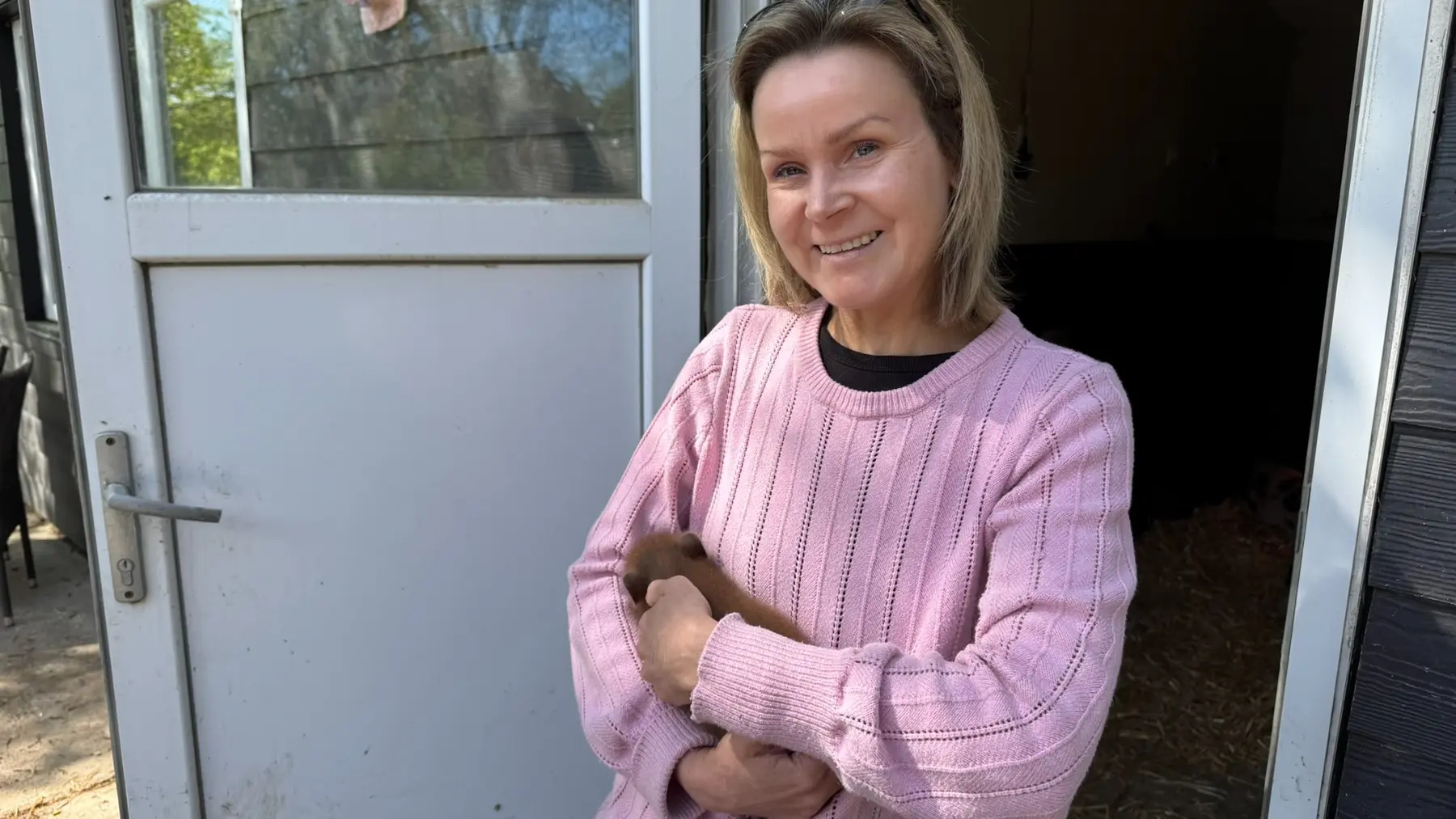 Helle smiler foran en åben dør